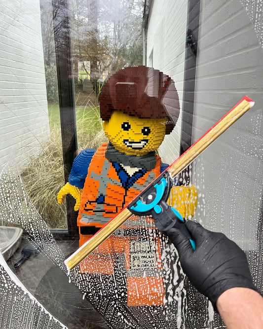 Window Cleaner using Moerman Excelerator to Clean Glass With Lego Figurine Behind Glass Smiling