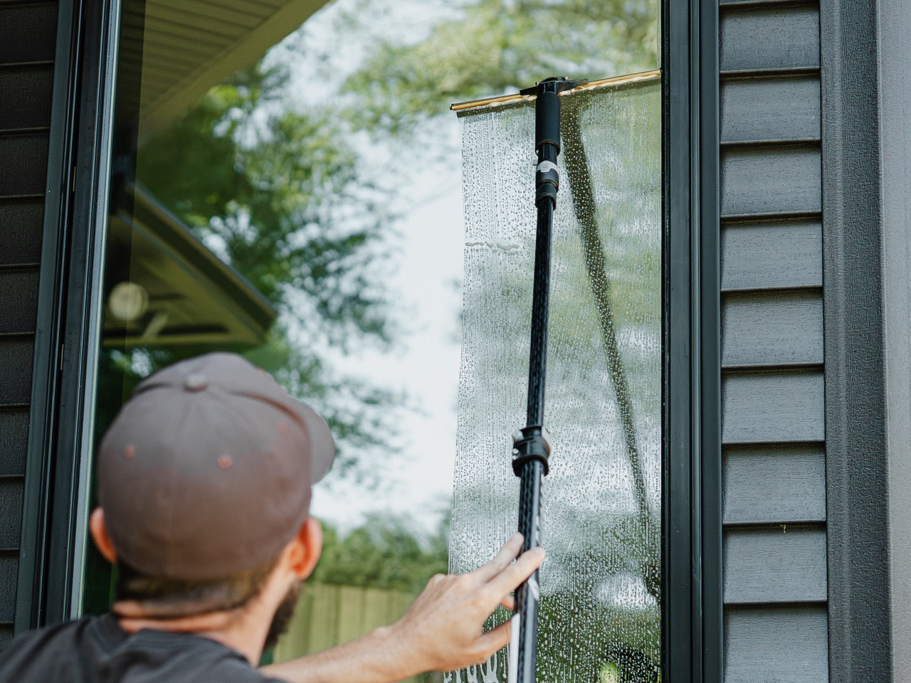 Unger Ninja Carbon Pole with a Squeegee Cleaning a Window