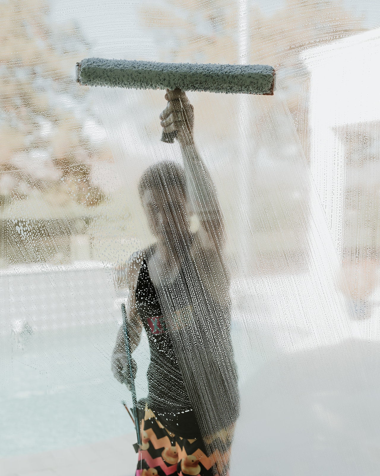 Window cleaner uses a scrubber and squeegee to clean a large pane of glass.